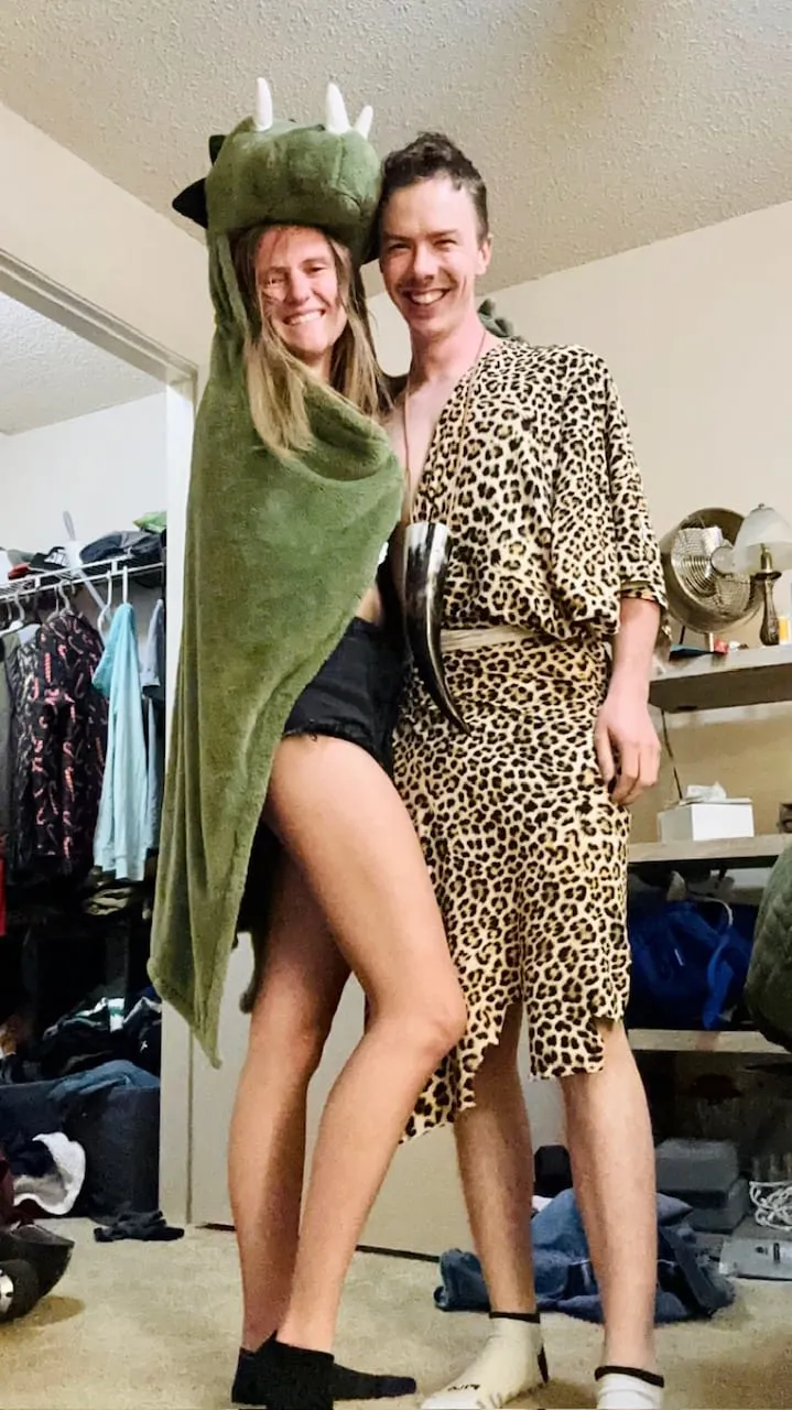 The couple in playful dinosaur and caveman Halloween costumes